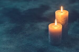 Two burning candles on navy blue background